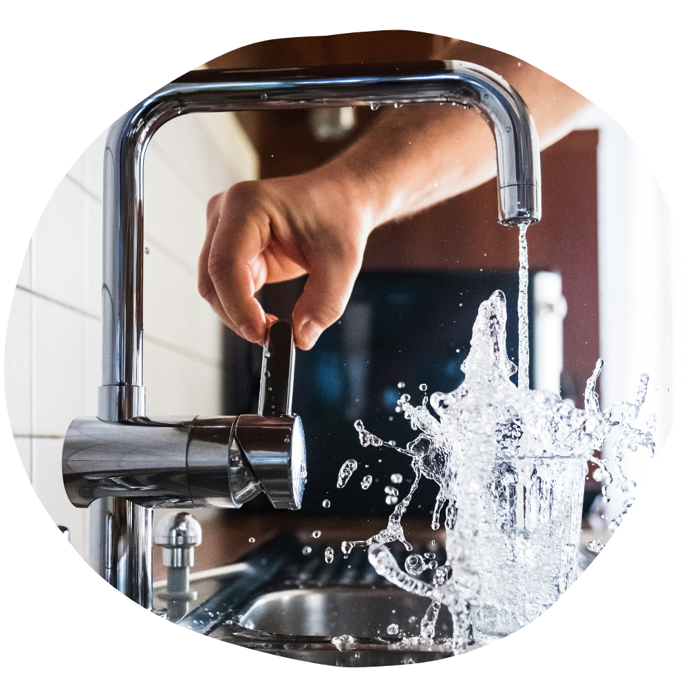 Stockphot mit Wasserhahn und Leitungswasser, dass in ein Glas Wasser sprudelt